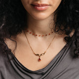 Model styled in 18k gold-plated Nominal jewelry featuring the Garnet Stone Keffiyeh Necklace layered with the Essential Red Agate Micro Chain.
