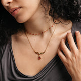 Model styled in 18k gold-plated Nominal jewelry featuring the Garnet Stone Keffiyeh Necklace layered with the Essential Red Agate Micro Chain.