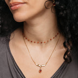 Model styled in 18k gold-plated Nominal jewelry featuring the Garnet Stone Keffiyeh Necklace layered with the Essential Red Agate Micro Chain.