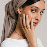 Model wearing a ring stack featuring an 18k gold-plated Five-Stone Bezel Band stacked above a Bezel Band on the index finger, an Olive Branch Marquise Bezel Ring on the middle finger, and a Triple Marquise Bezel Ring on the ring finger.