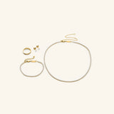 18k gold-plated Tennis Essentials & Ring Set featuring the Tennis Necklace, Tennis Bracelet, Tennis Earrings and Intertwined Bezel Ring.