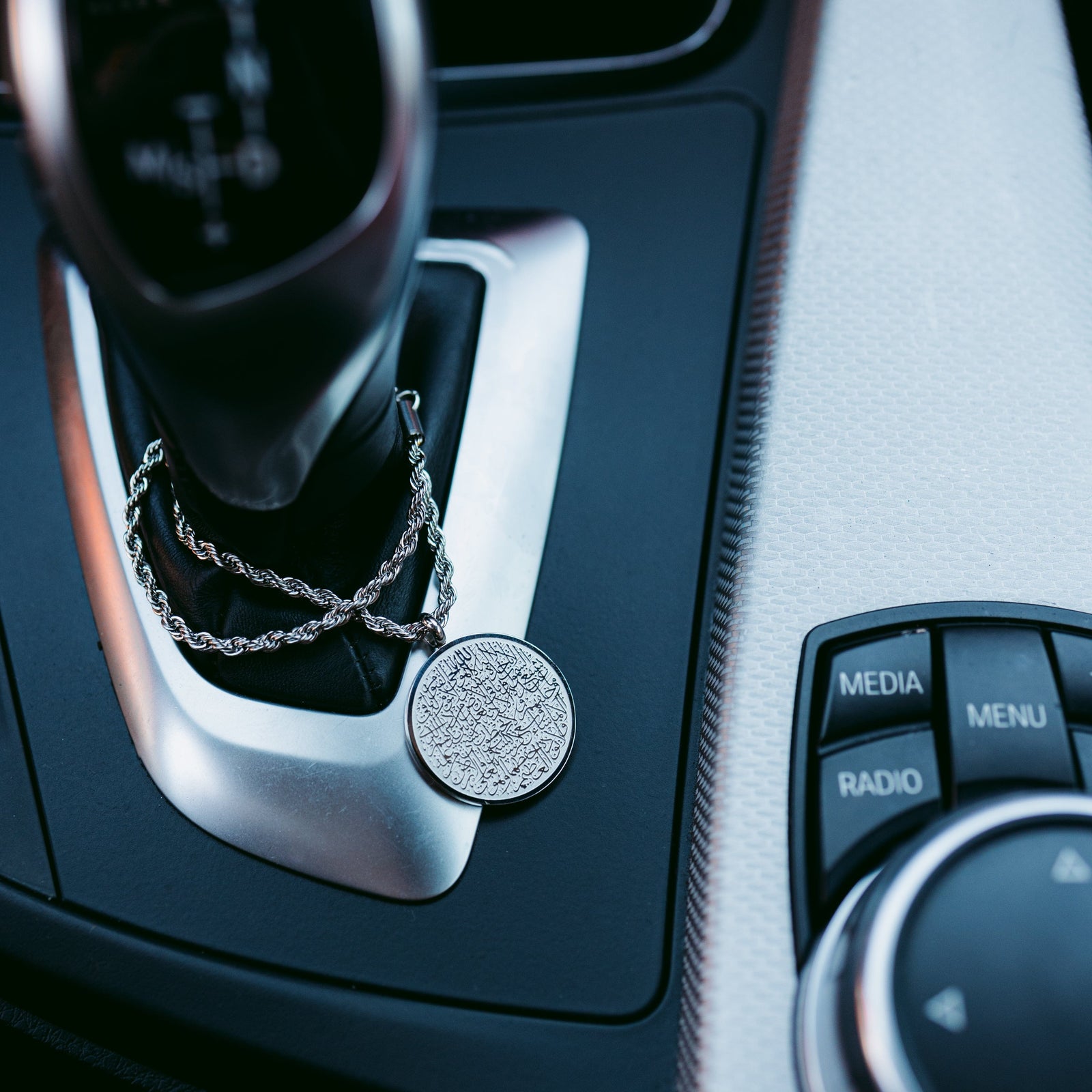 Close up of the silver Ayatul Kursi Car Hanger on a car gear stick.