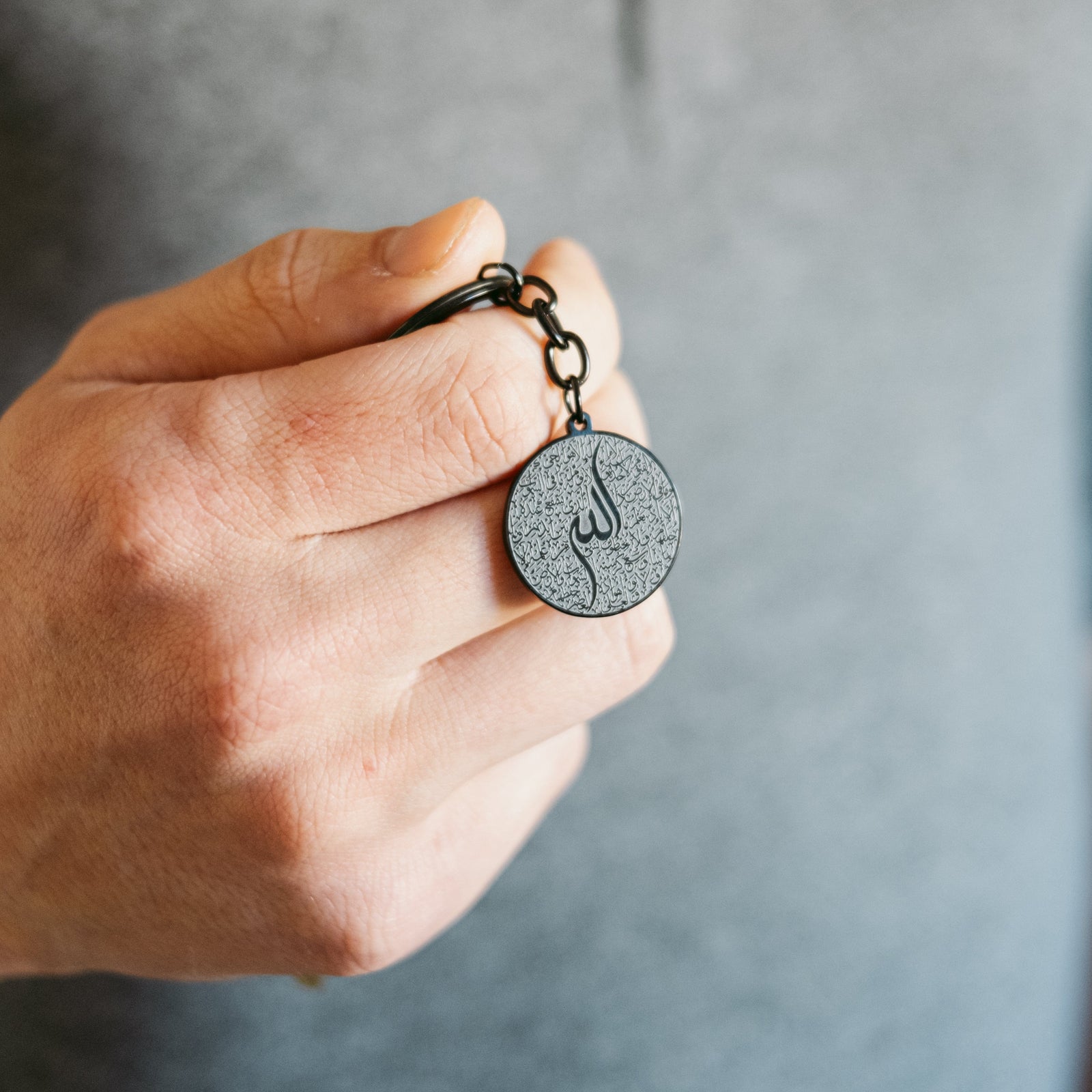Close up of the black Ayatul Kursi Keychain V2 as the model holds the keychain.