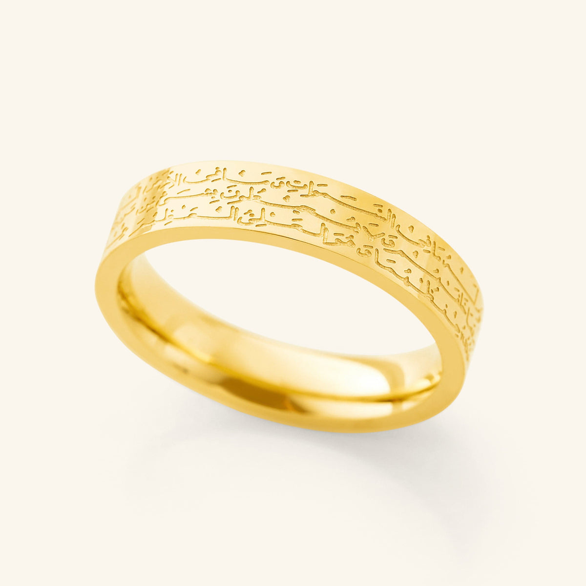 Close-up of a gold band ring engraved with Arabic Ayatul Kursi script.