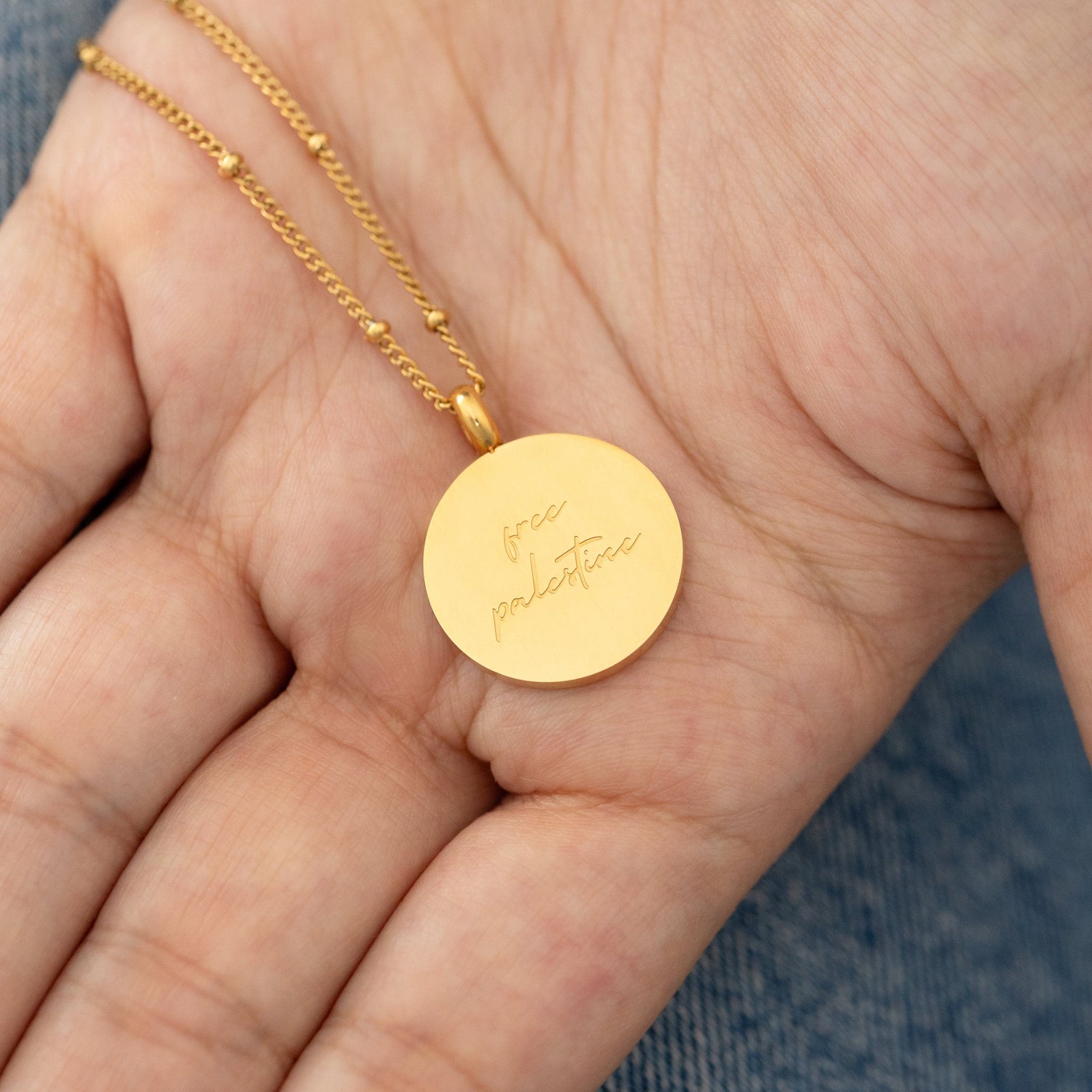 Back of a Gold Al-Aqsa ‘Free Palestine’ Necklace showing english text that reads "Free Palestine"
