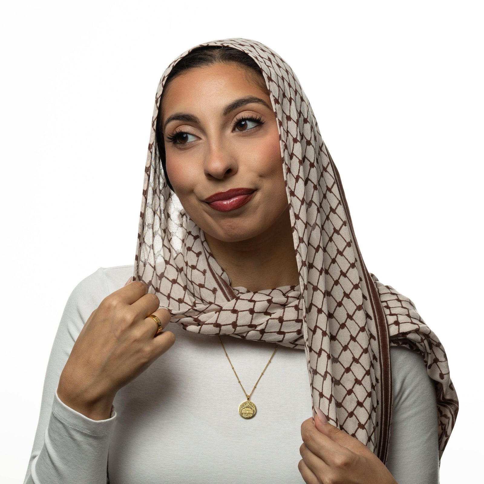 Woman wearing a keffiyeh patterned headscarf and a gold Al-Aqsa ‘Free Palestine’ Necklace on a white background