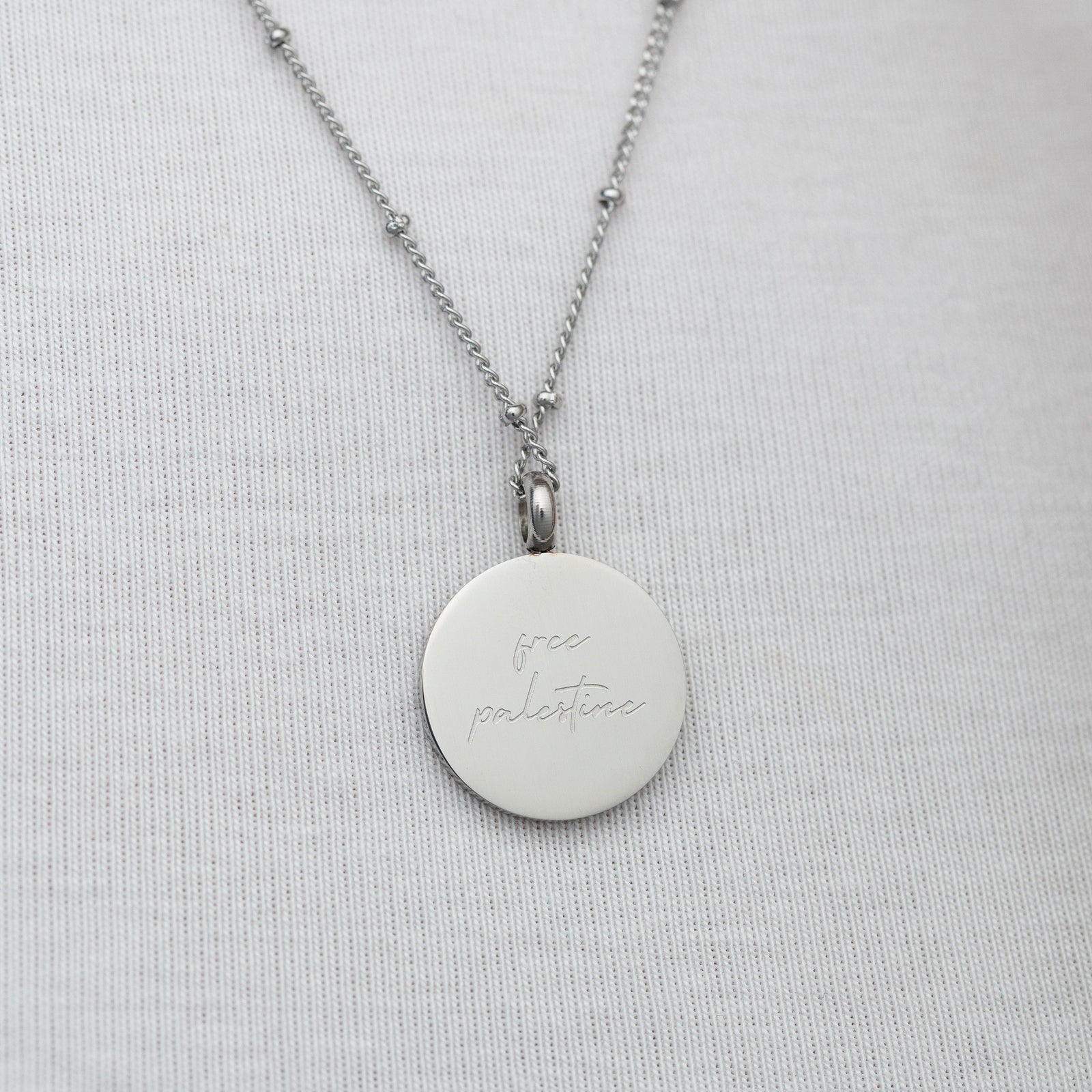 Back of Al-Aqsa ‘Free Palestine’ Necklace engraved with 'free Palestine' on a light gray background
