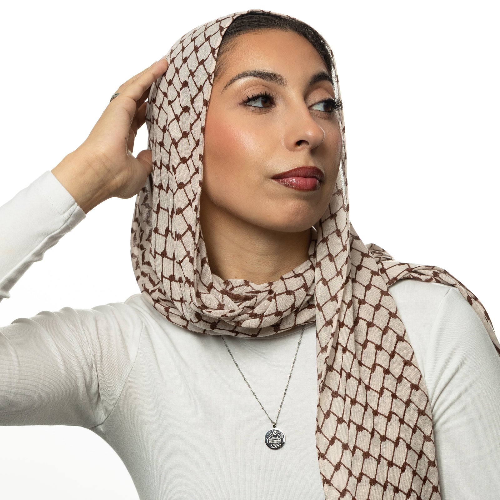 Woman wearing a patterned headscarf, white shirt and a silver Al-Aqsa ‘Free Palestine’ Necklace