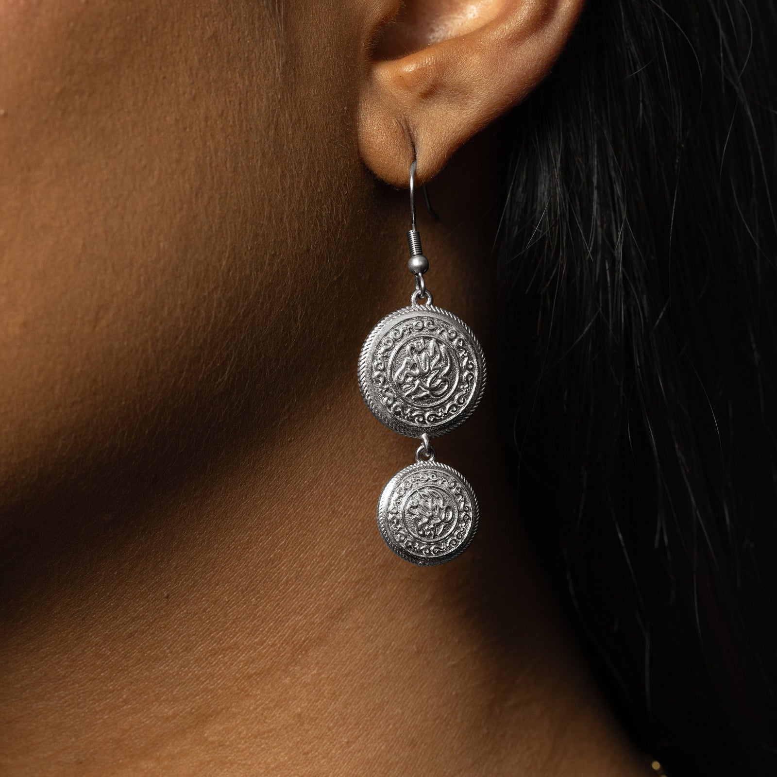 Close up of the gold Alhamdulillah Coin Earring as worn by the model on their left ear.