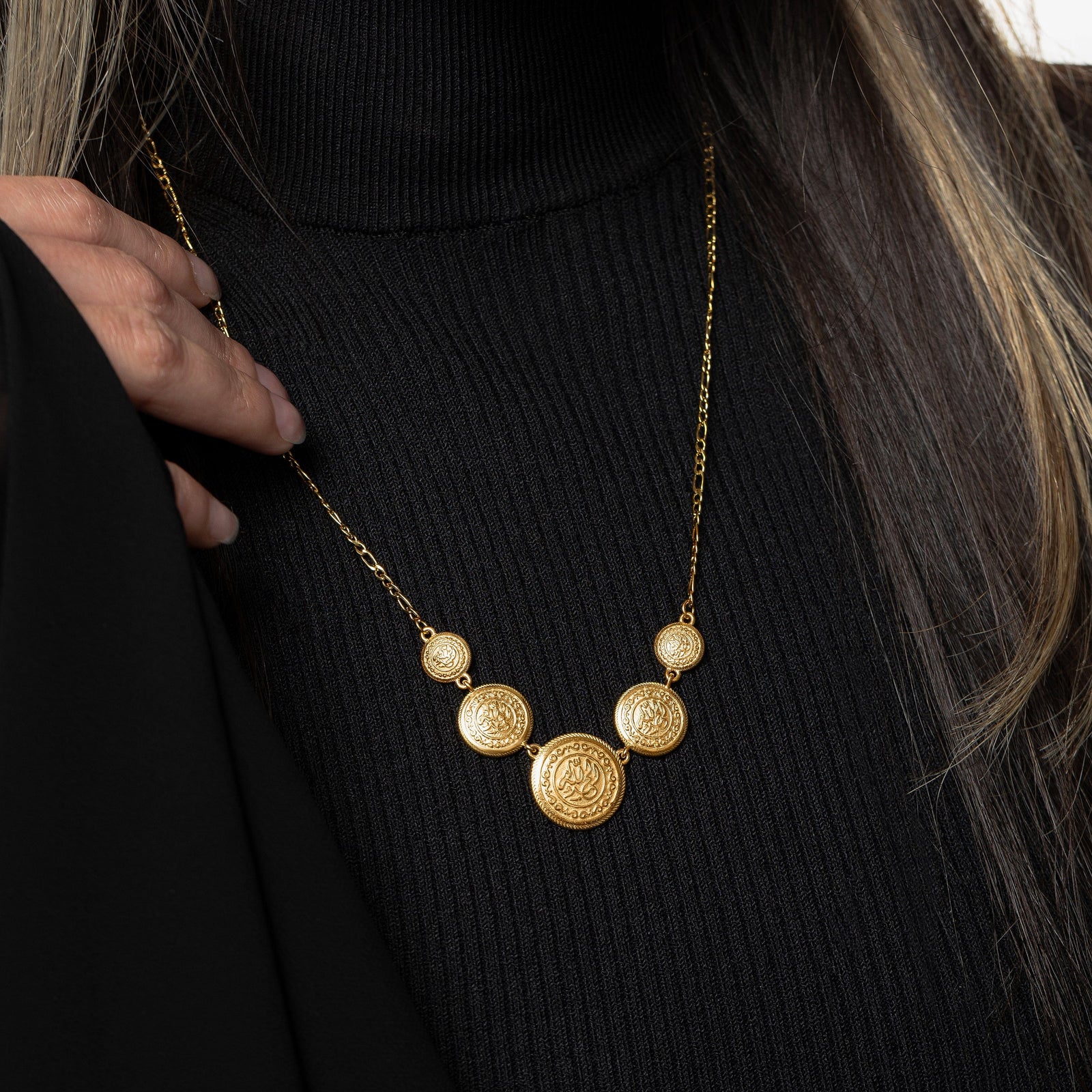 Model wearing the gold Alhamdulillah Coin Necklace, touching its thin chain.