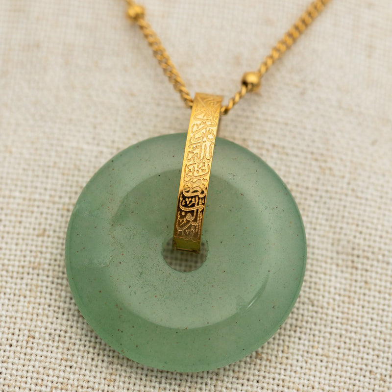 Close-up of the polished green aventurine pendant necklace laid flat pimage_ showing natural texture in the stone and engraved details on the gold bail.