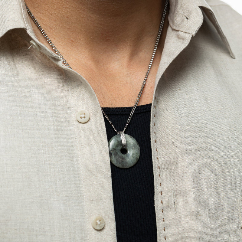 Chest-level view of the labradorite stone pendant necklace resting over a black ribbed shirt with a beige button-down.
