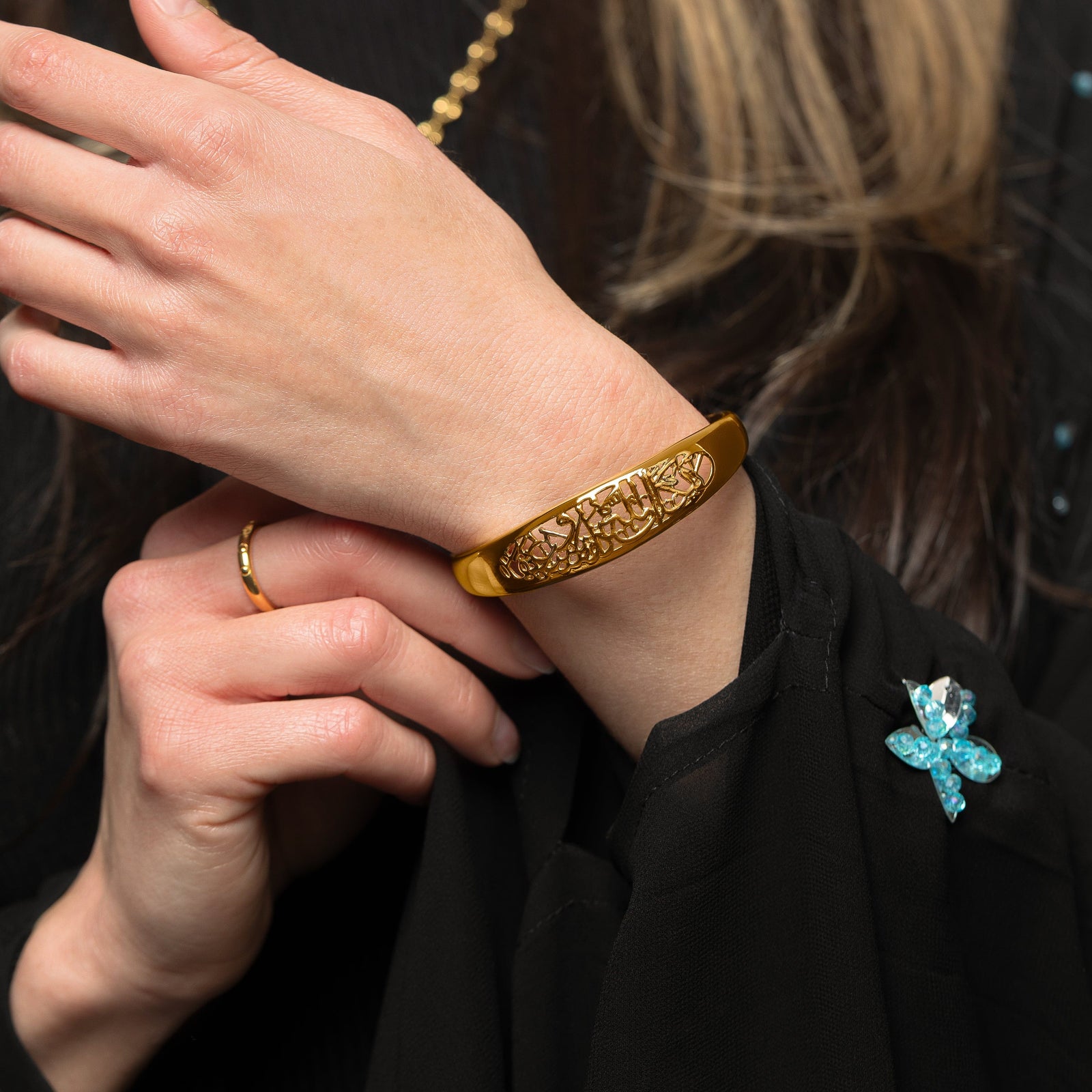 Model wears the gold "Allah does not burden a soul beyond what it can bear" Openwork Bangle on their left wrist.