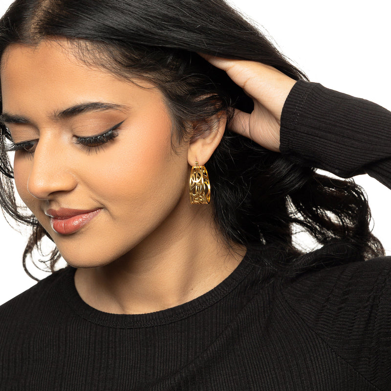A woman wearing the gold “Allah does not burden a soul beyond what it can bear” Earrings pimage_ styled with a black ribbed top
