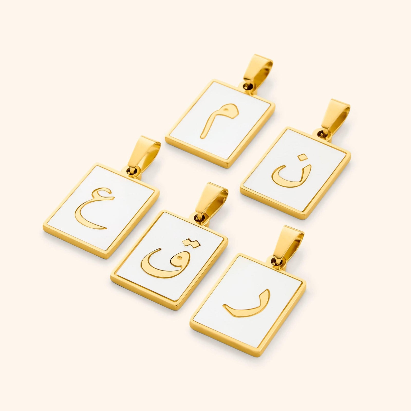 A collection of five Arabic letter charms in 18K gold plating, each featuring an iridescent pearl backdrop. The charms are engraved with Arabic letters.