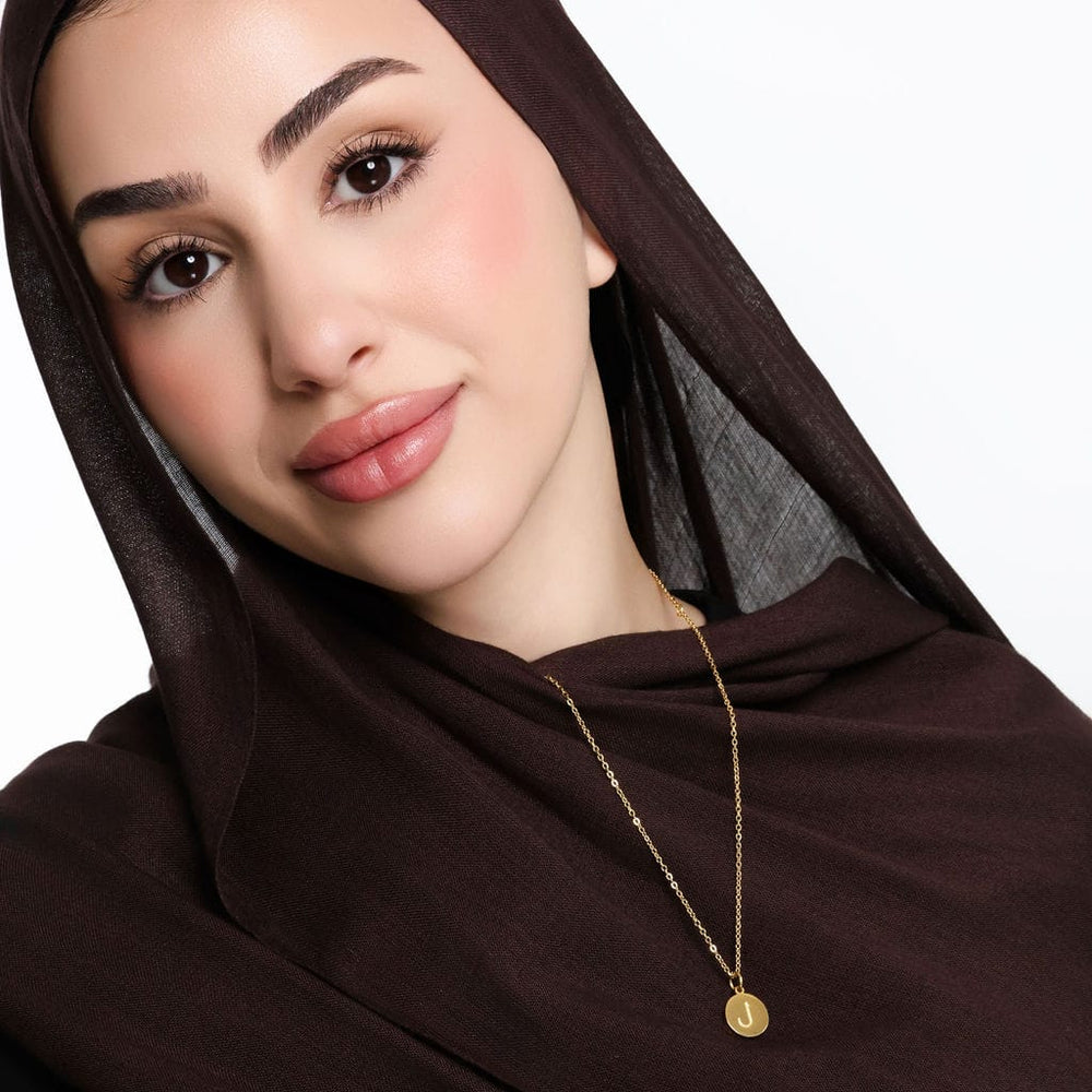 Photo of the model smiling to the camera. The model is wearing the gold Arabic Letter Necklace.