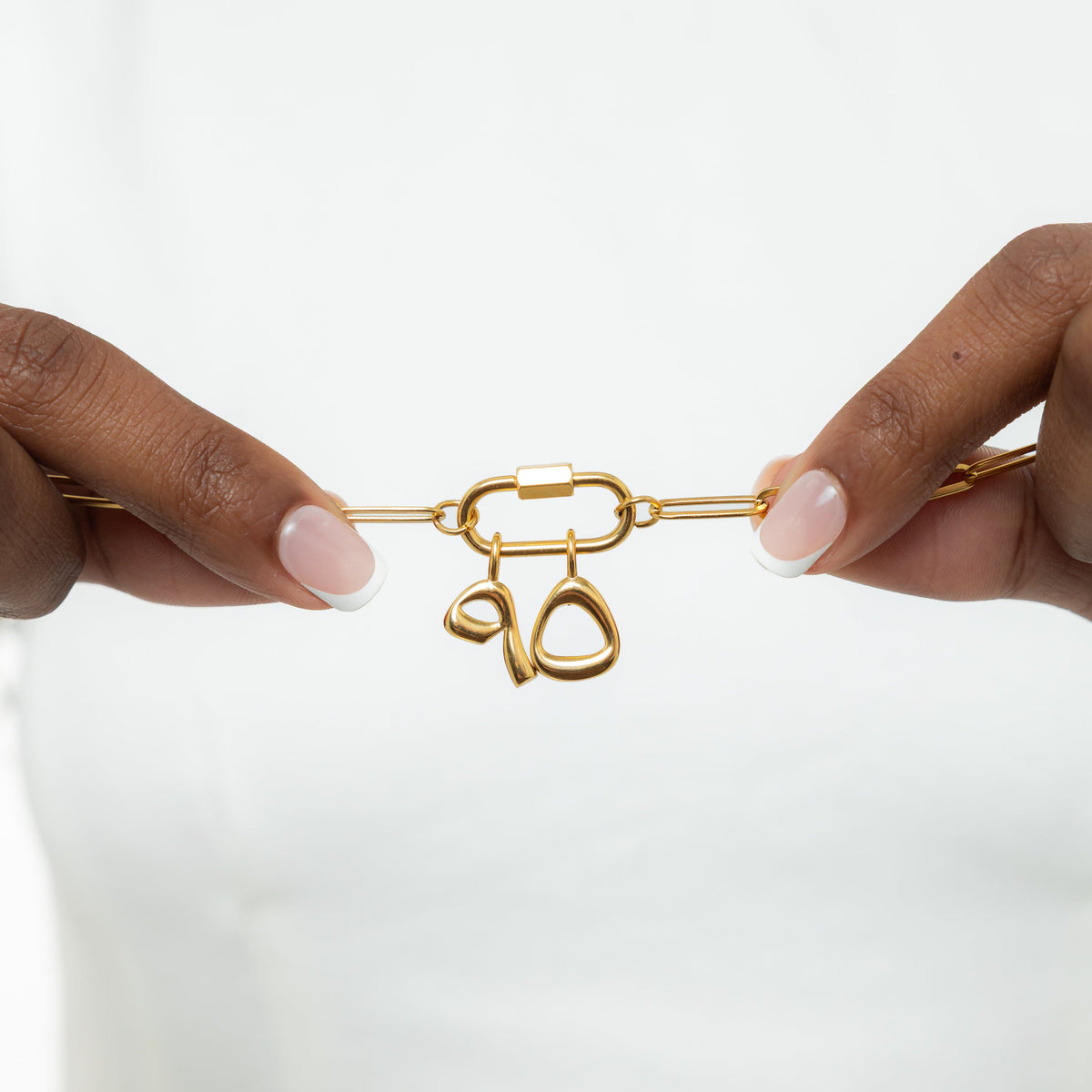 Close-up of the gold-plated Arabic number charms "5 and 9" with an iridescent pearl background, polished and detailed.