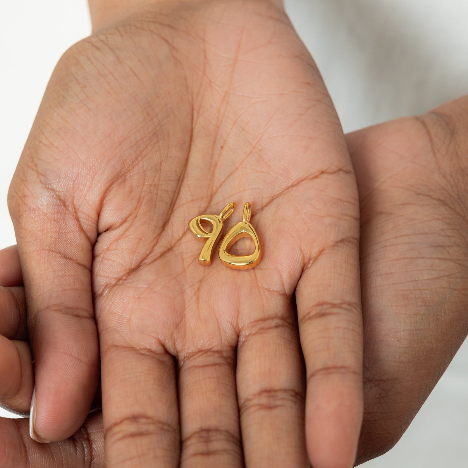 Close-up of the gold-plated Arabic number charms "5 and 9" with an iridescent pearl background, polished and detailed.