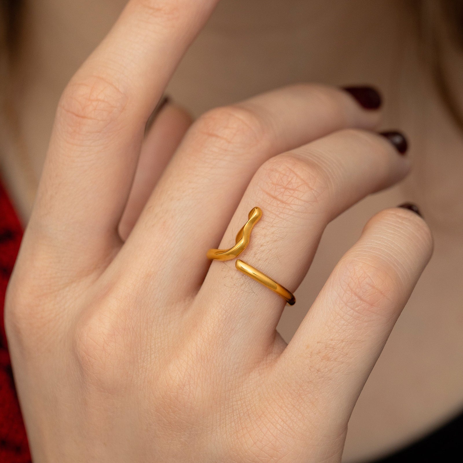 Close up photo of the model's hand, gold Arabic Letter Wrap Ring worn on their right ring finger.