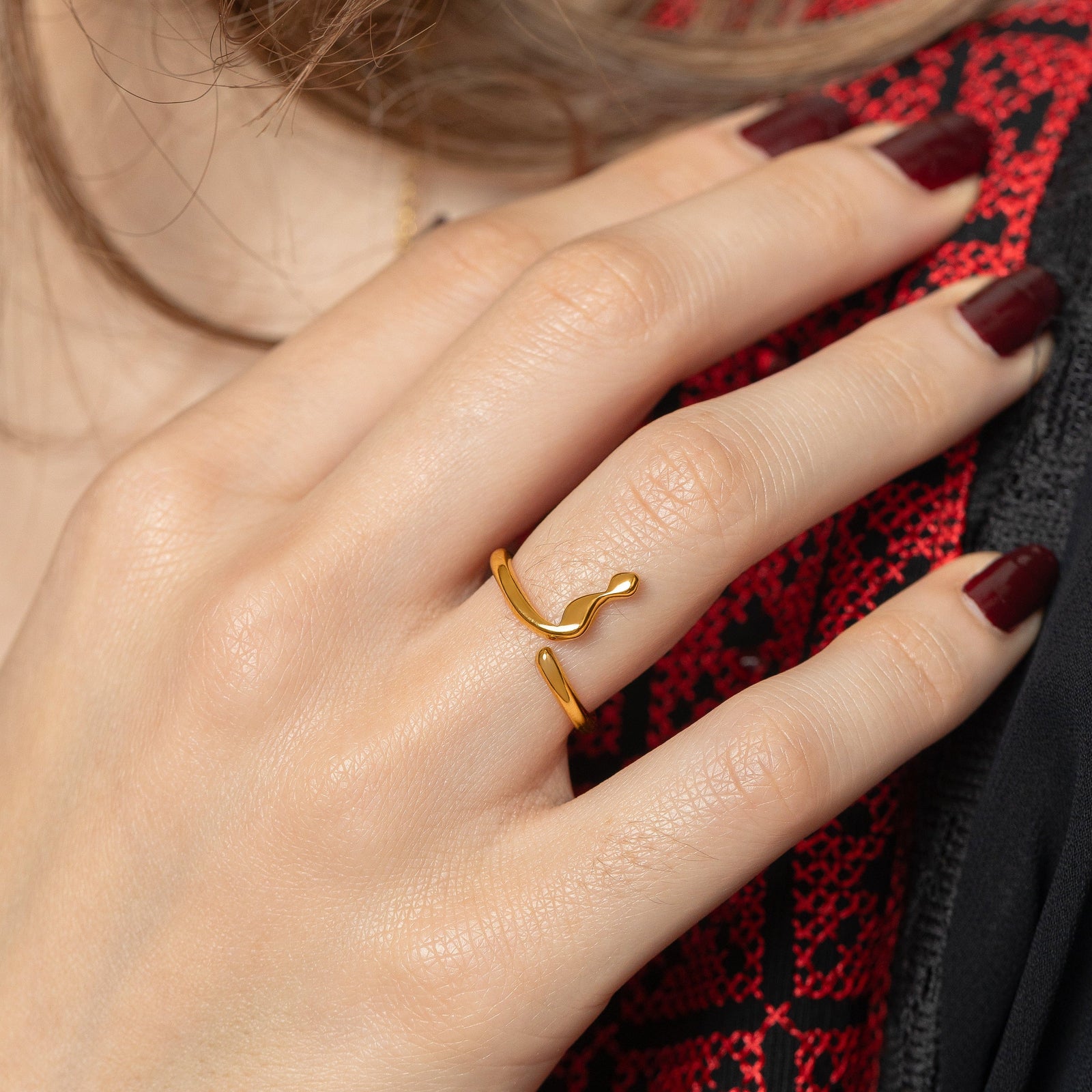 Close up photo of the model's hand, gold Arabic Letter Wrap Ring worn on their right ring finger.