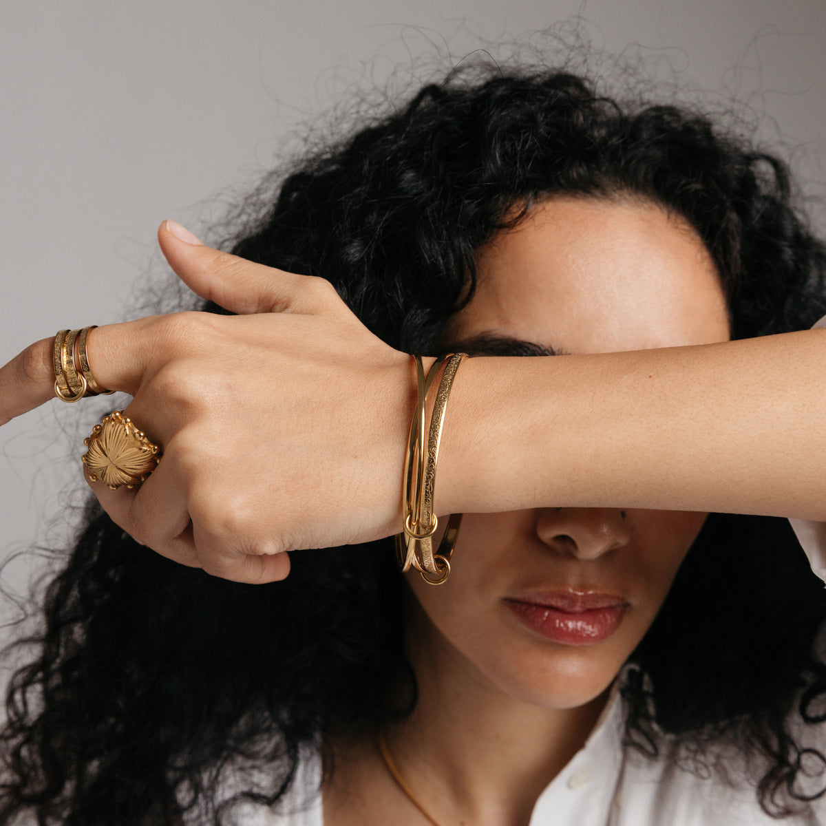 Model styled in 18k gold-plated Nominal jewelry featuring the Ayatul Kursi Bangle Stack paired with the Ayatul Kursi Ring Stack and Dome Statement Ring.