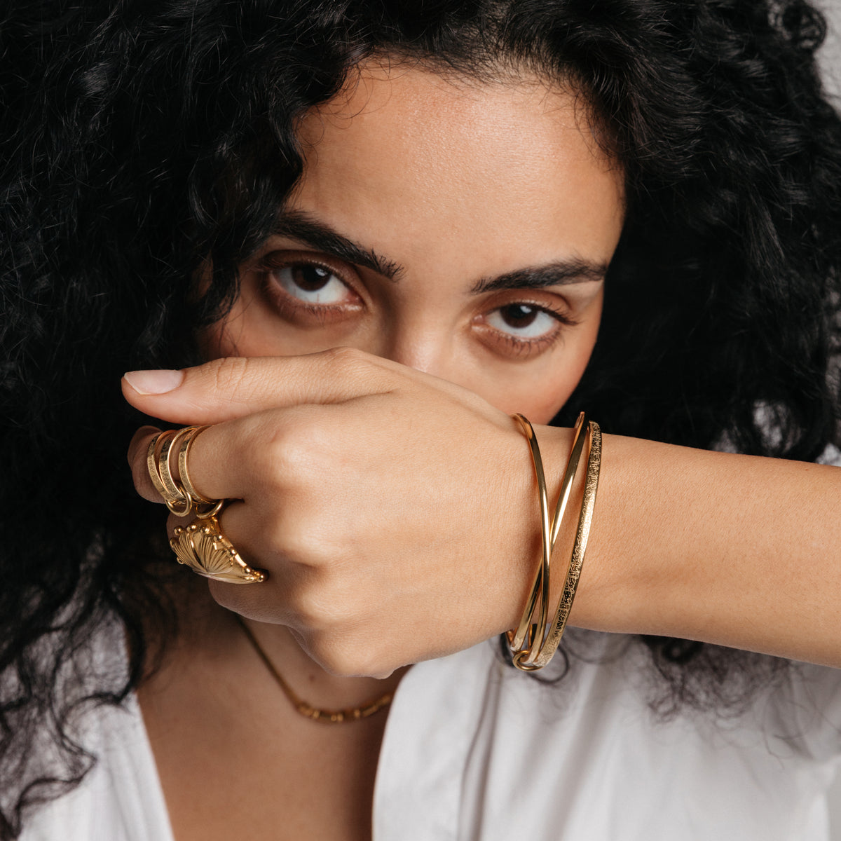 Model styled in 18k gold-plated Nominal jewelry featuring the Ayatul Kursi Bangle Stack paired with the Ayatul Kursi Ring Stack and Dome Statement Ring.