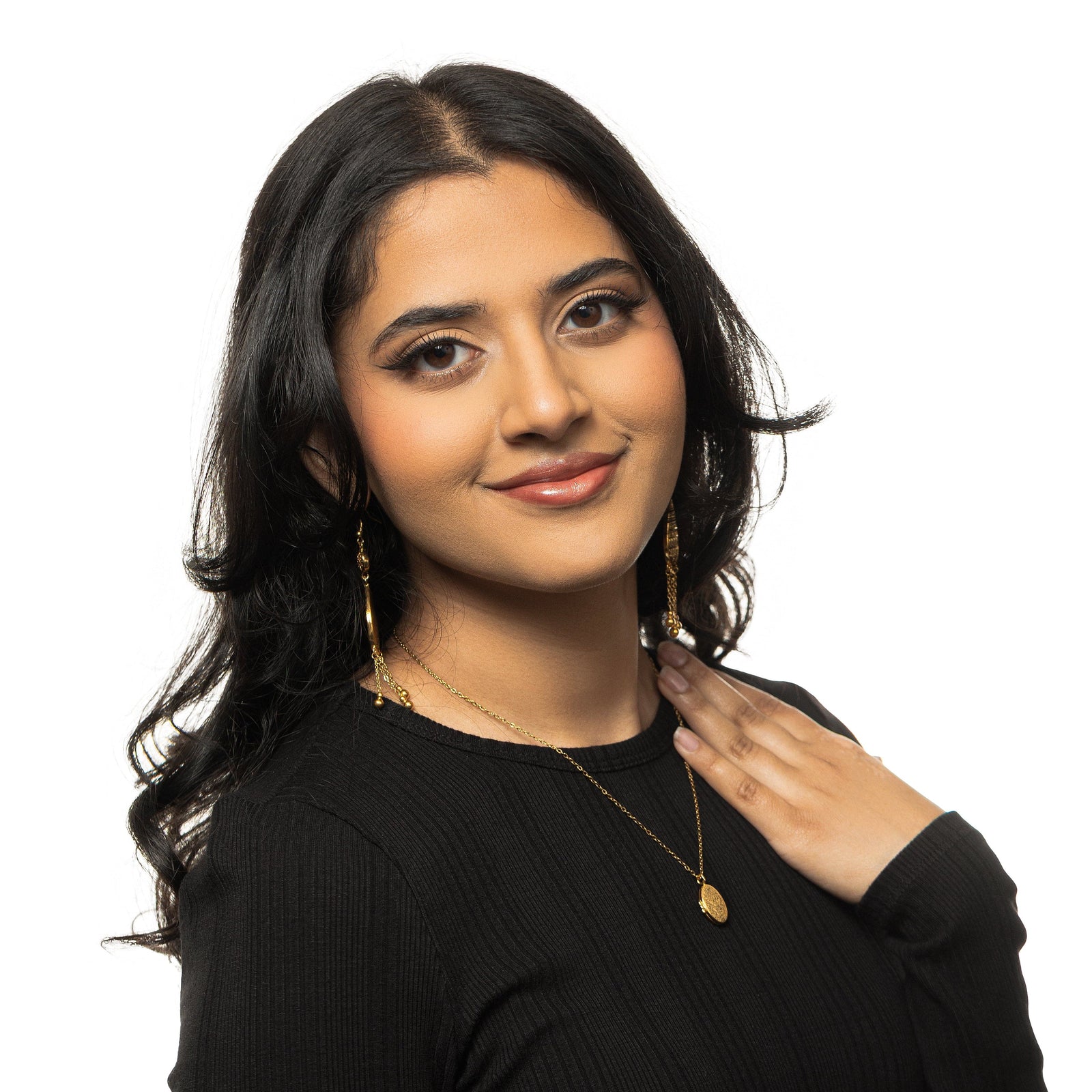 Gold Ayatul Kursi Locket worn over a black ribbed top, styled with gold earrings.