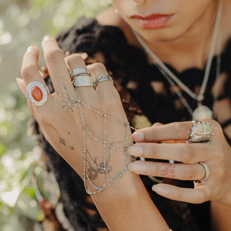 Silver Keffiyeh Fishnet Hand Chain styled with stacked silver rings and tattoos visible on the hand.