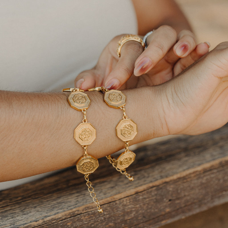 Two “Our Roots Run Deep” Dotted Bracelets in gold stacked on the wrist.