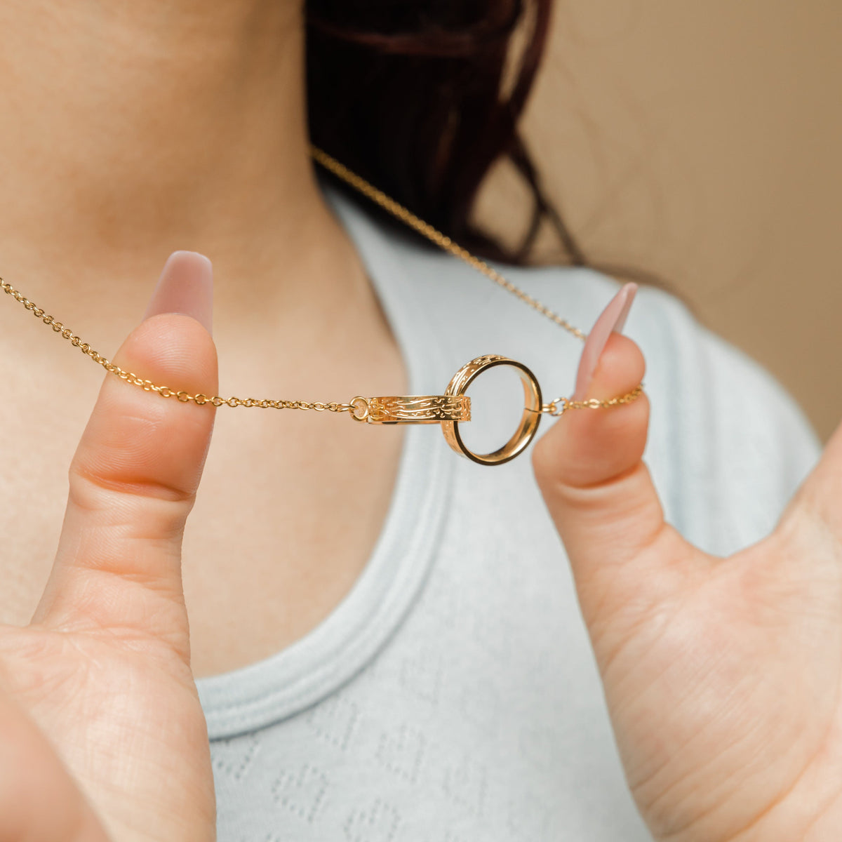 Close-up of a model wearing one of the interlocked necklaces, with the circular pendant resting on her collarbone, highlighting the Arabic inscription.