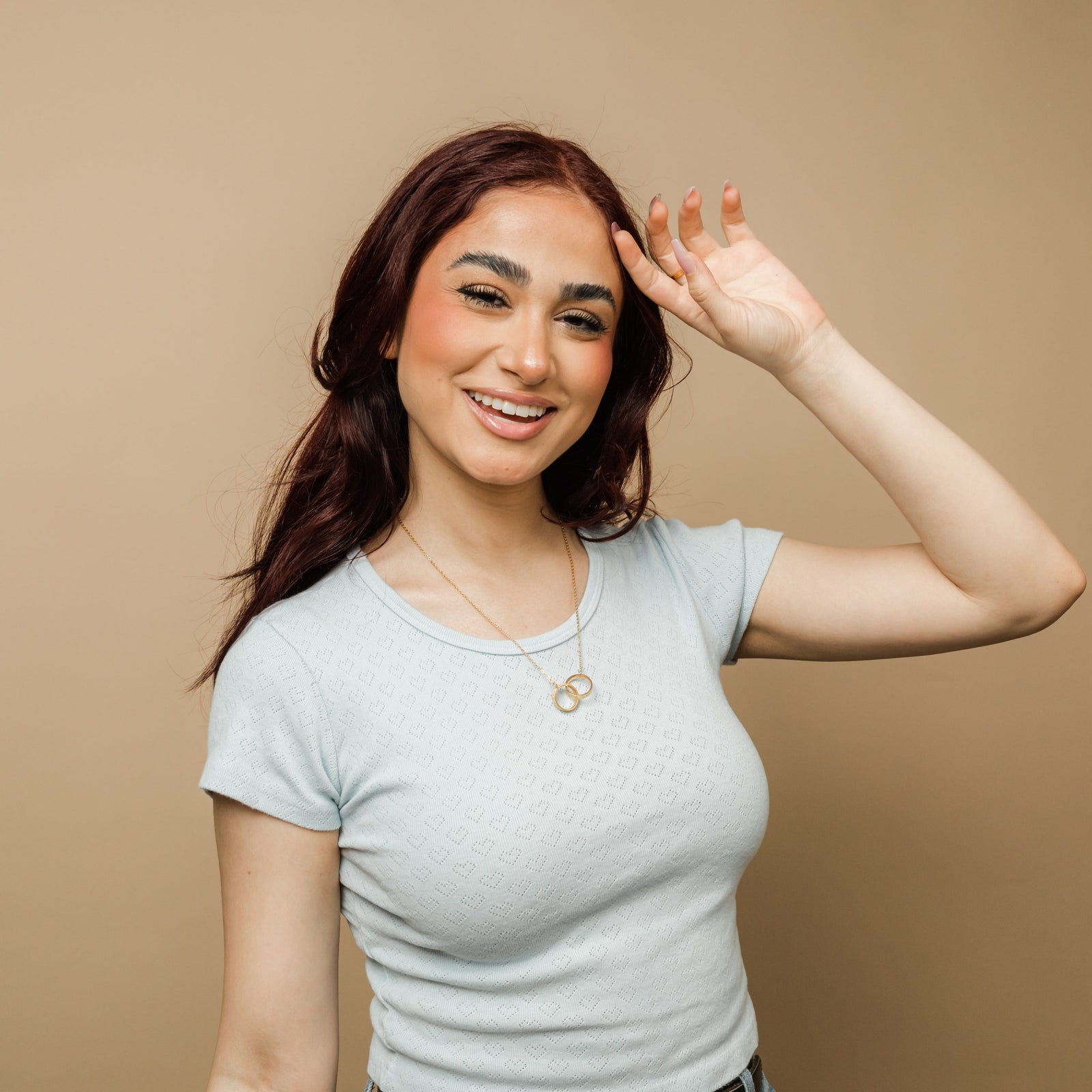 Close-up of a model wearing one of the interlocked necklaces, with the circular pendant resting on her collarbone, highlighting the Arabic inscription.