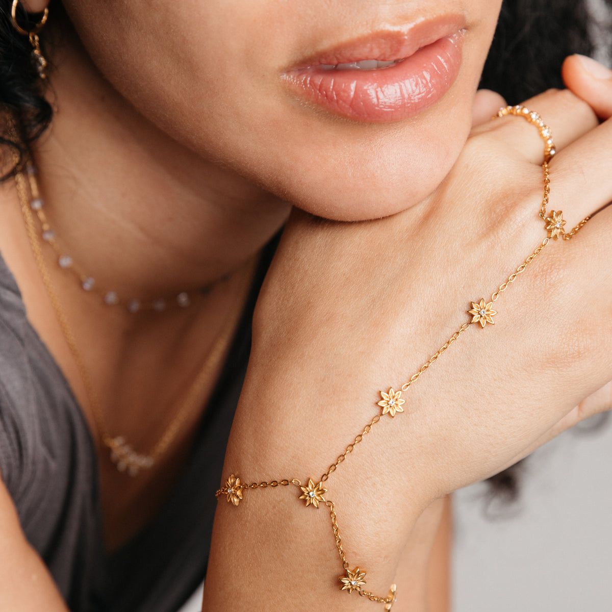 Model styled in 18k gold-plated Nominal jewelry featuring the Bezel Bloom Hand Chain paired with the Bezel Garden Ring and Essential Iolite Micro Chain.