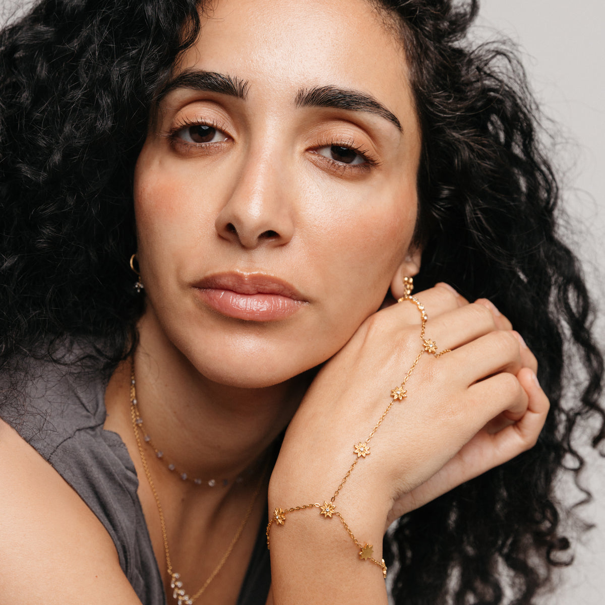 Model styled in 18k gold-plated Nominal jewelry featuring the Bezel Bloom Hand Chain paired with the Bezel Garden Ring and Essential Iolite Micro Chain.