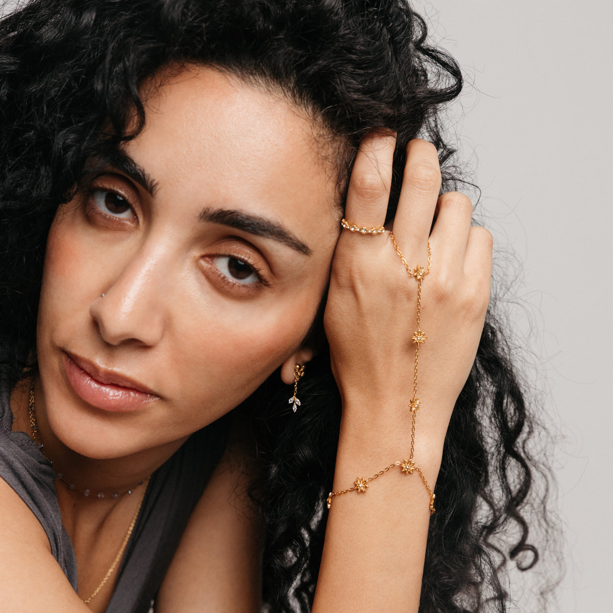 Model styled in 18k gold-plated Nominal jewelry featuring the Bezel Garden Ring paired with the Bezel Bloom Hand Chain, Essential Iolite Micro Chain, and Pavé Raining Olive Branch Drop Earrings