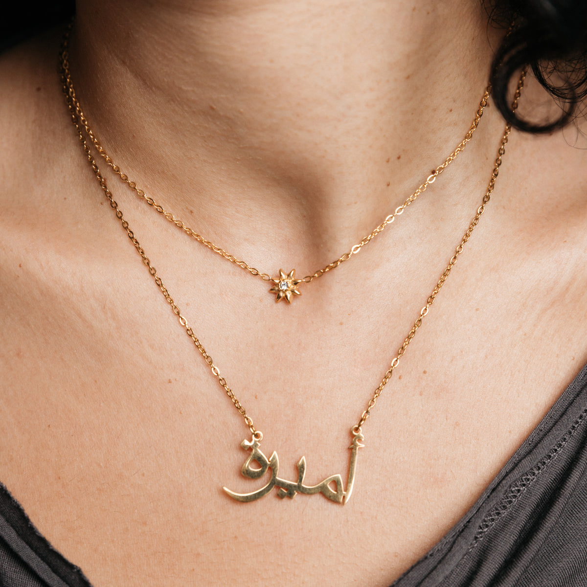 Model styled in 18k gold-plated Nominal jewelry featuring the Bezel Bloom Necklace layered with an Arabic Ready Name Necklace.