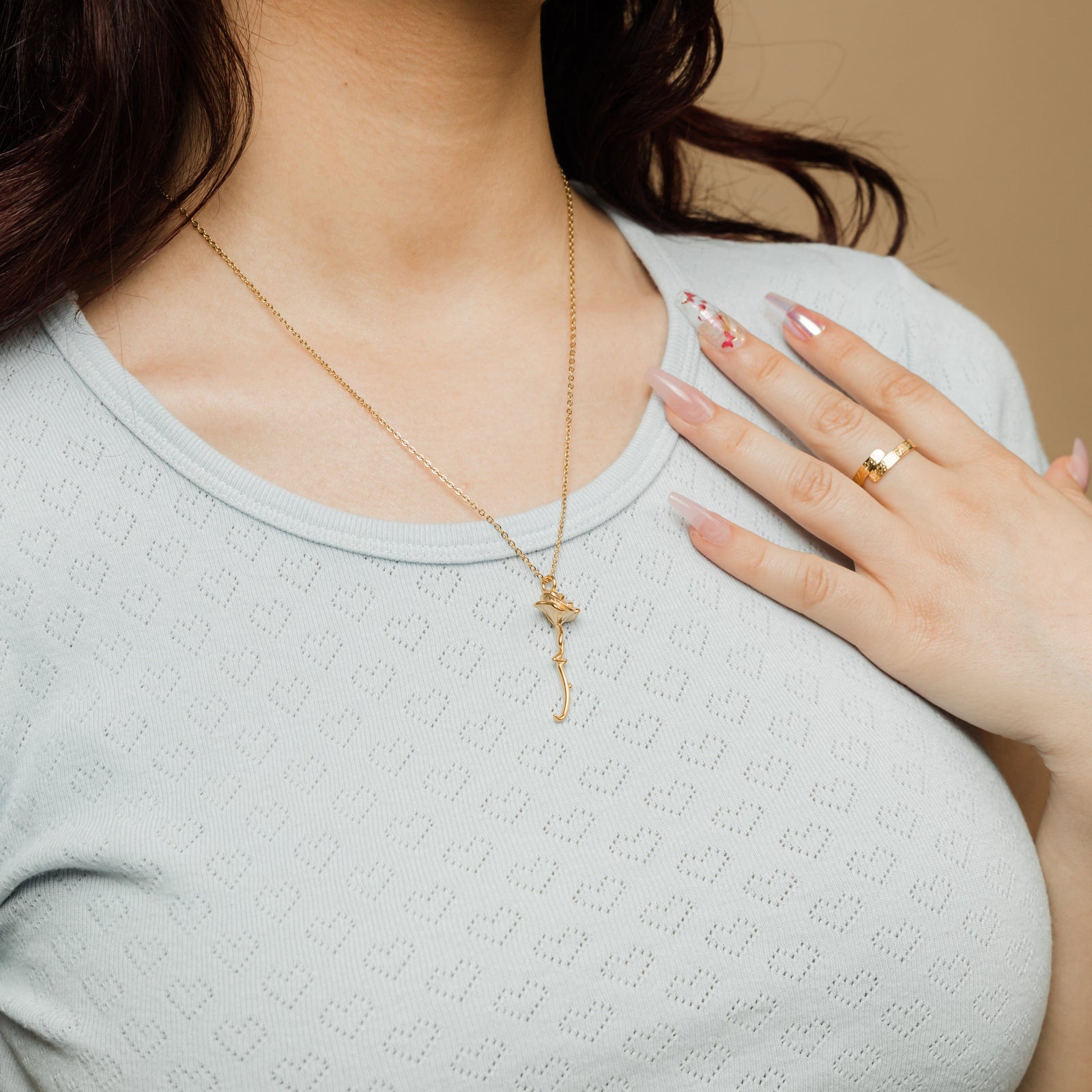 Close up of the gold Blooming Love Necklace against the light colored fabric of the model's shirt.
