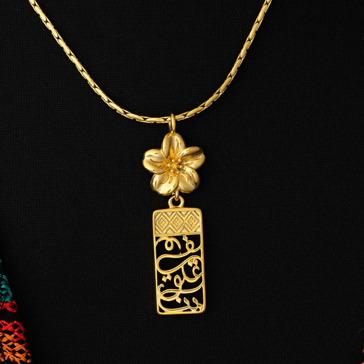 Close up photo of the Blooming in Our Hearts pendant on a black background.