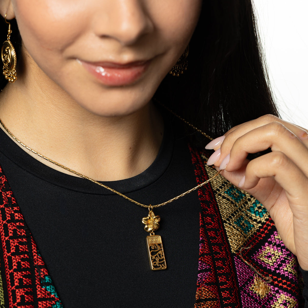 Model wearing the Blooming in Our Hearts Necklace holding the gold chain.