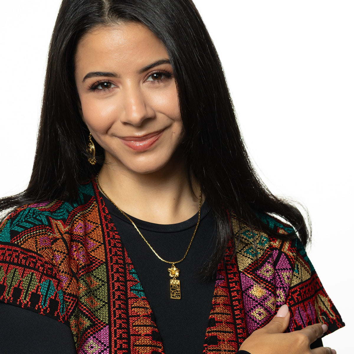 Photo of a model smiling and posing for the camera as they wear the Blooming in Our Hearts necklace around their neck.