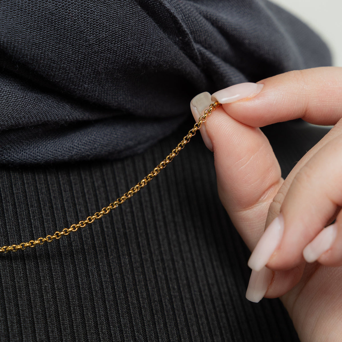 Close up of the gold Micro Box Chain as the model pulls the chain to show it closer to the camera.