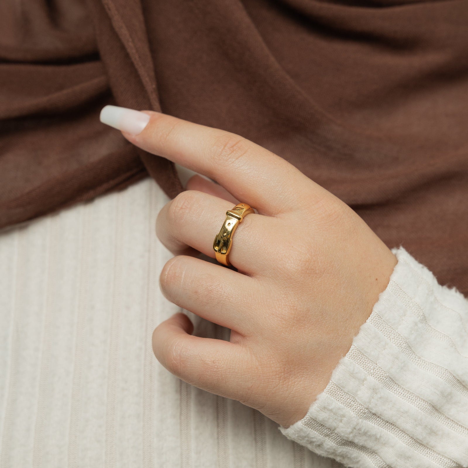 Gold buckle ring on a woman's finger.