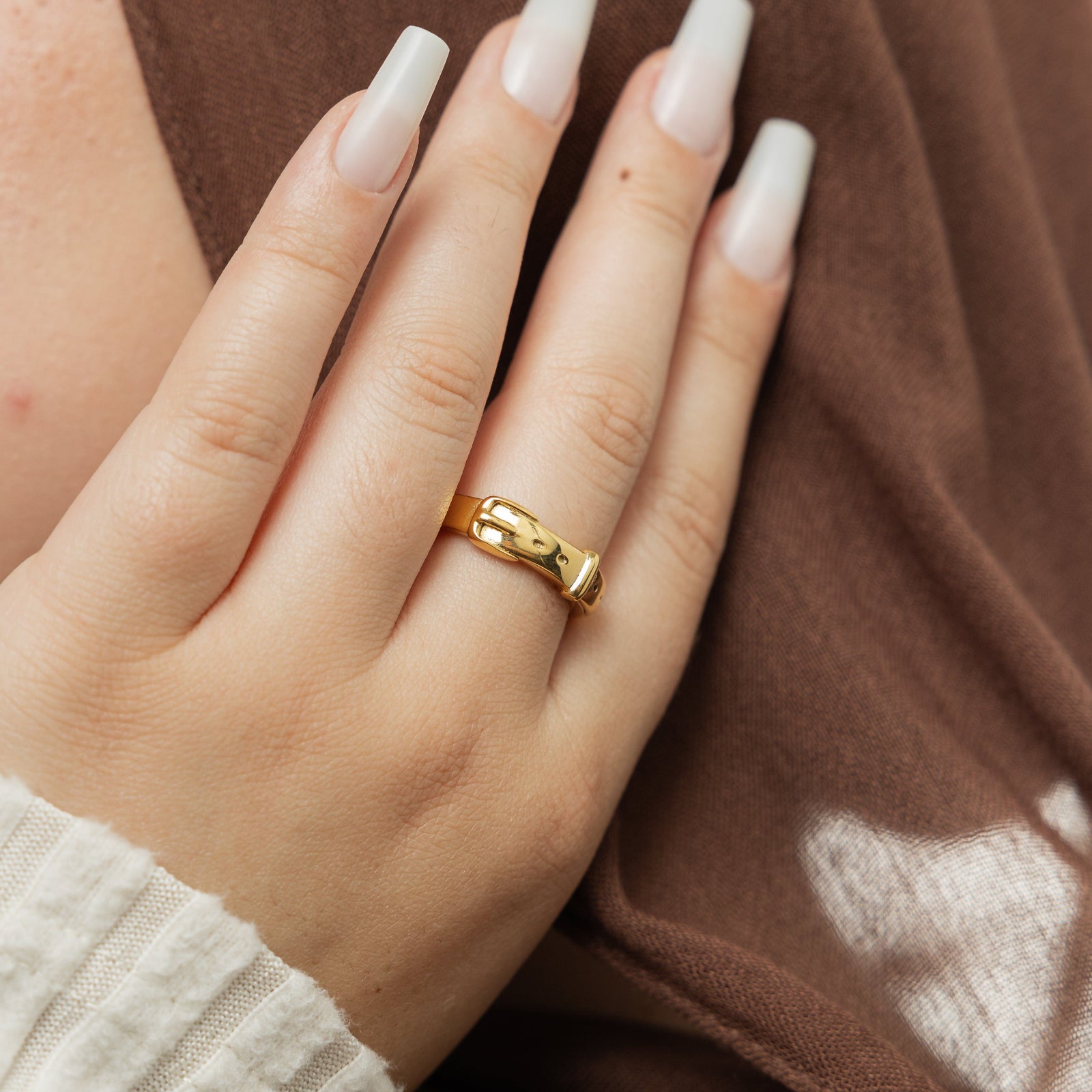 Gold buckle ring on a woman's finger.