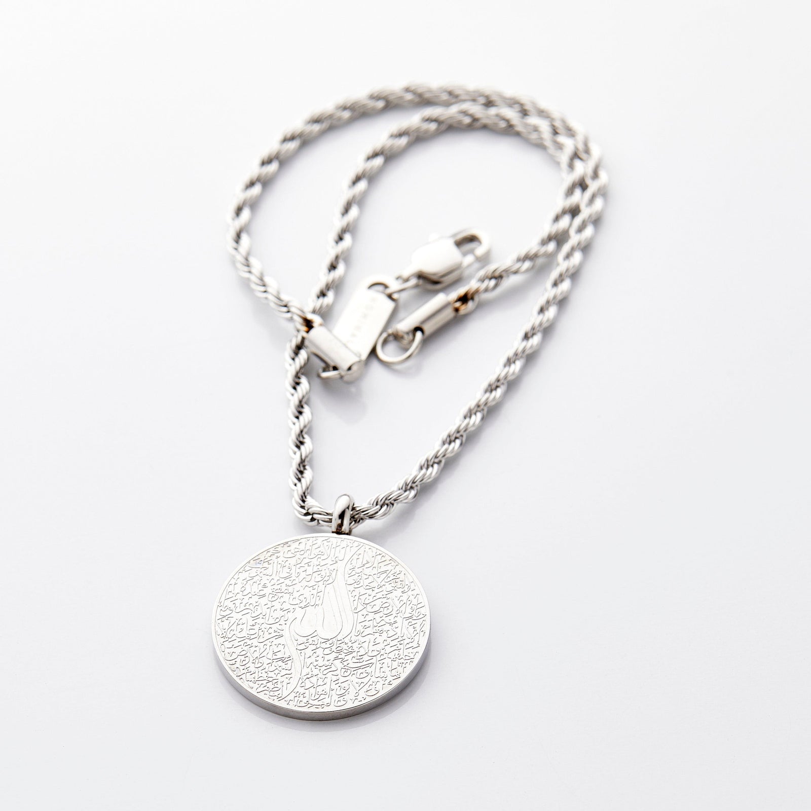 Silver car hanger with a circular pendant engraved in Arabic calligraphy of Ayatul Kursi, styled flat against a neutral background.