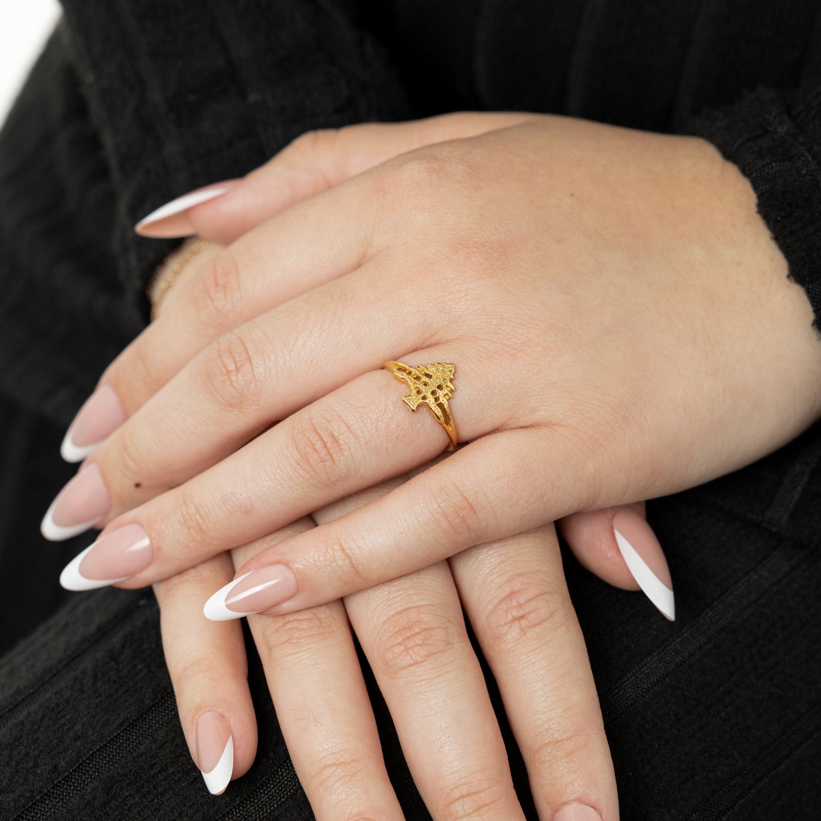 Woman wearing a gold Cedar of Lebanon ring on her finger, with the textured tree design visible.