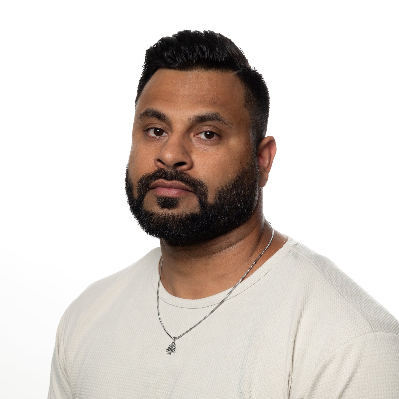 Man wearing a silver Cedar of Lebanon necklace with a white textured shirt.