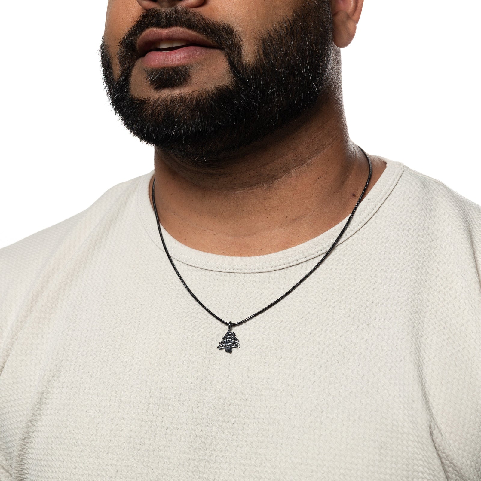Black Cedar of Lebanon necklace worn over a white textured shirt.
