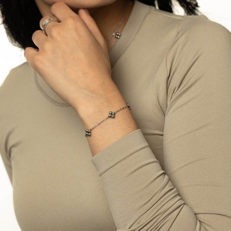 Silver bracelet worn on wrist with a beige long-sleeve top.