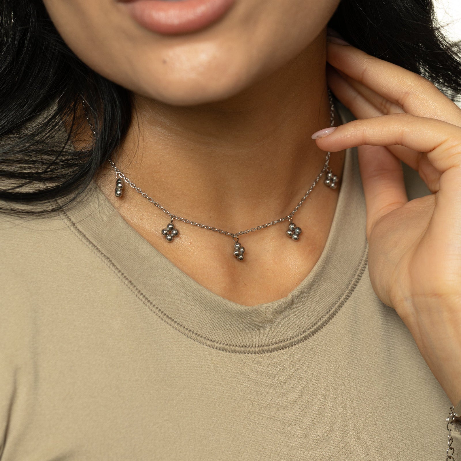 Woman wearing the silver Henna Choker close to the neckline, hand resting near collar.