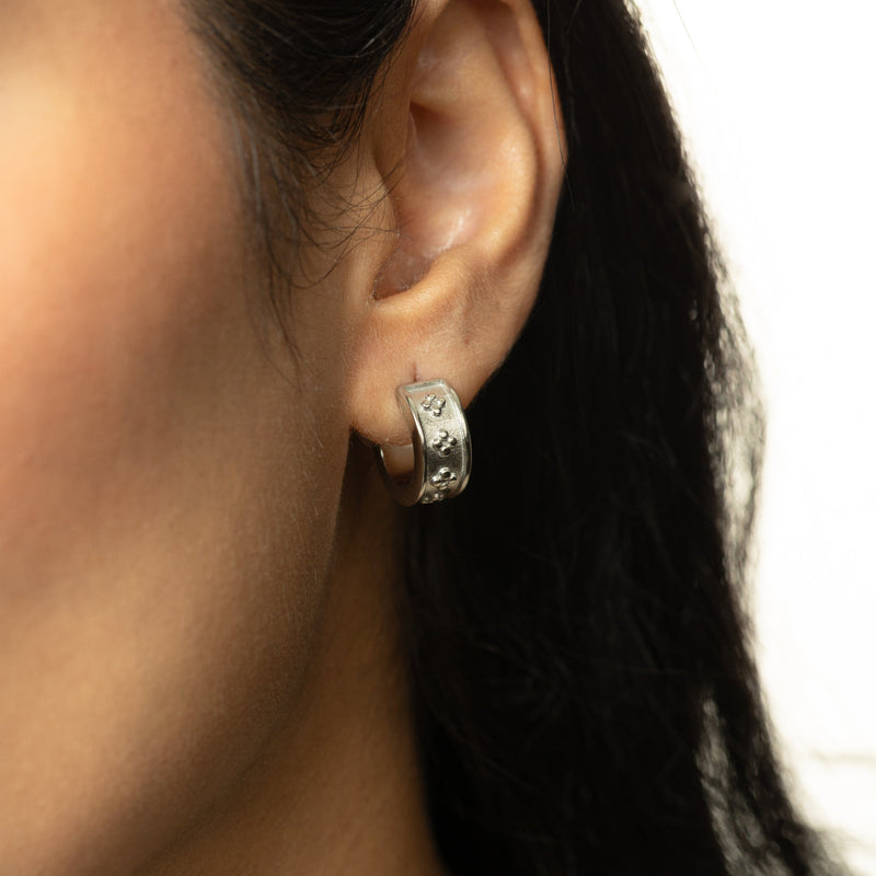 Close-up of silver Henna Hoop worn on ear pimage_ textured band with raised dotted floral details visible.