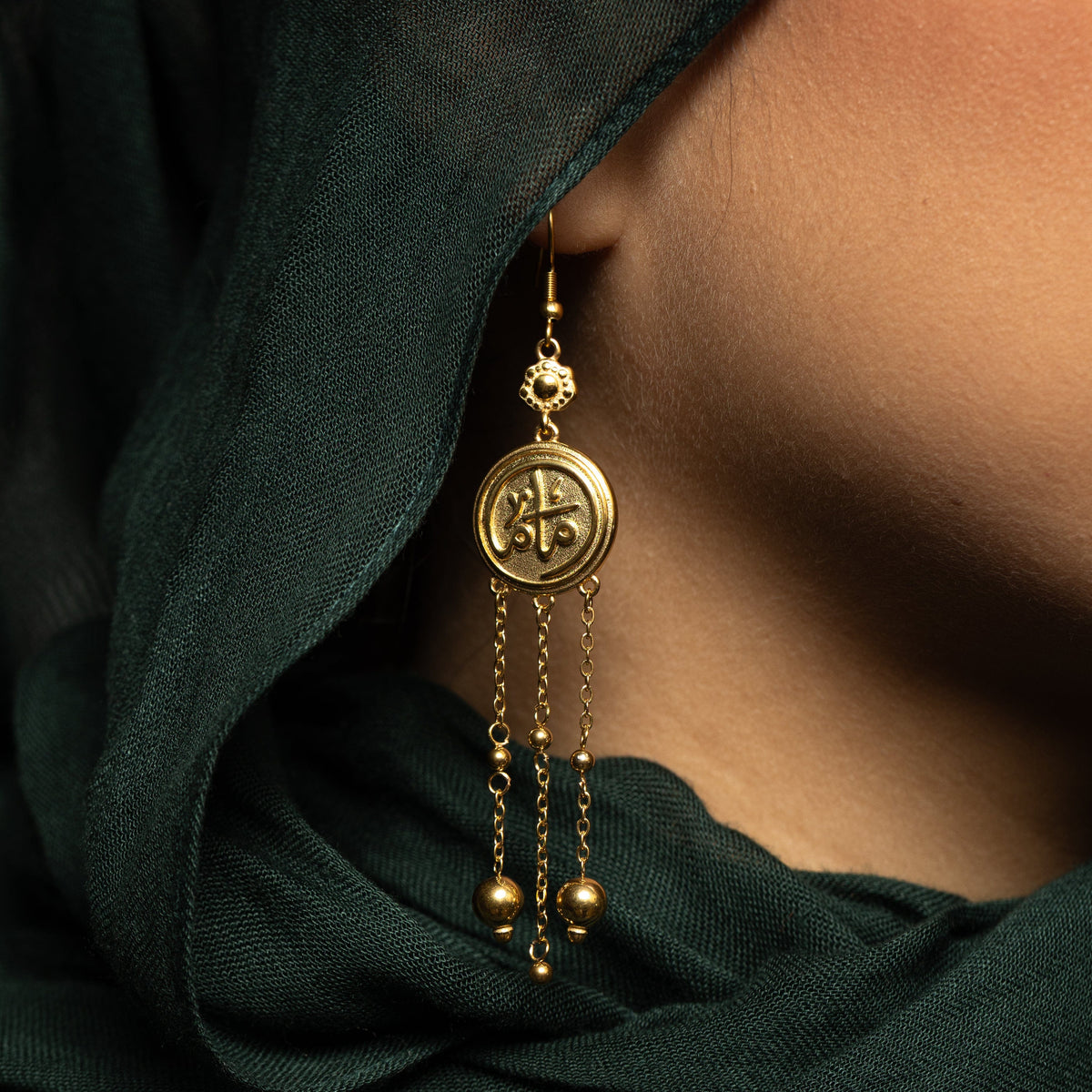 Close up of the gold coin Mama Earrings worn by a model.